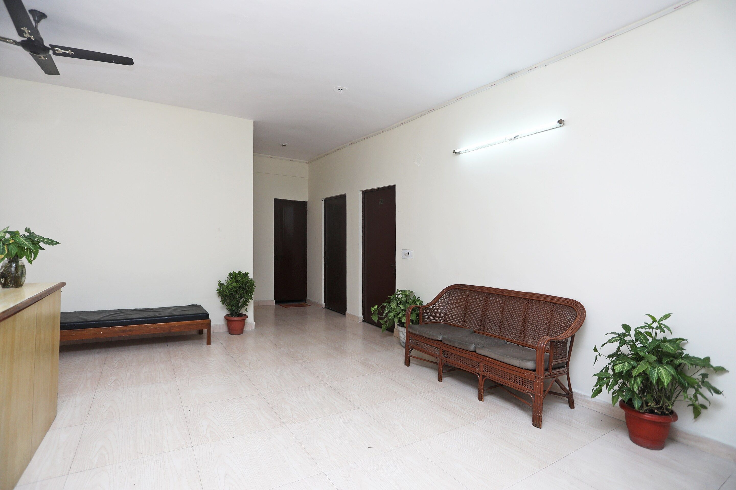 Una habitación amplia con un banco de madera, un sofá y dos plantas en macetas.