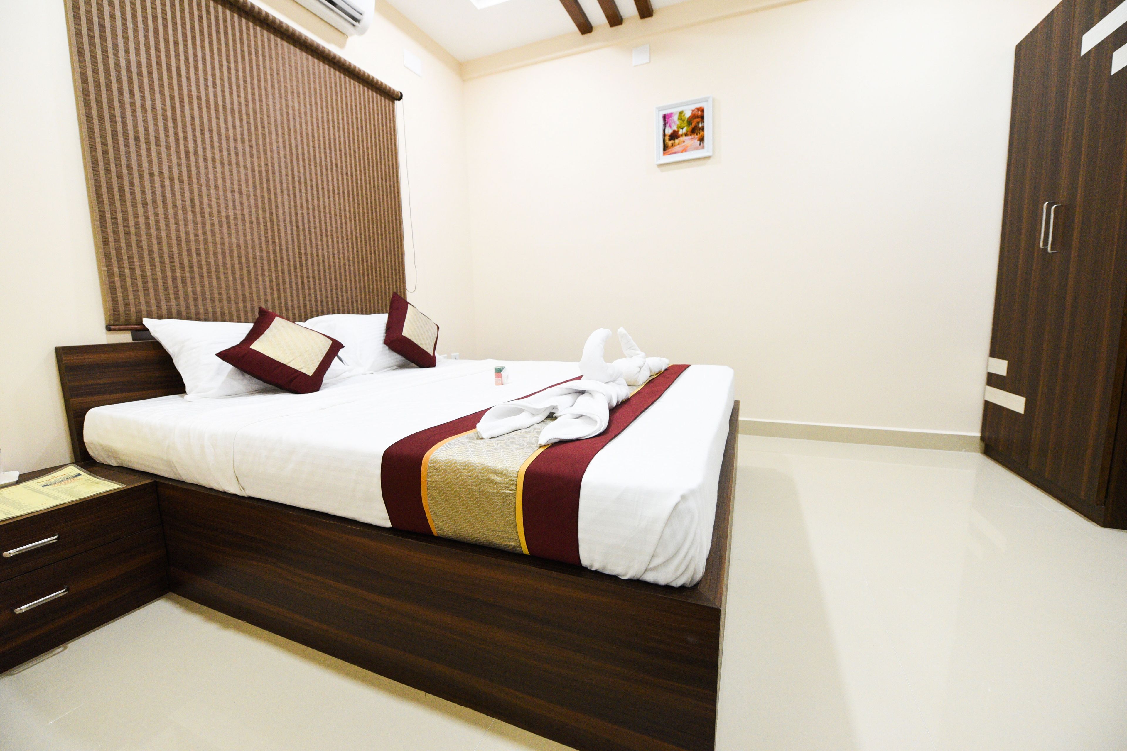 A neatly made bed with a wooden headboard, a bedside table, and a wardrobe.