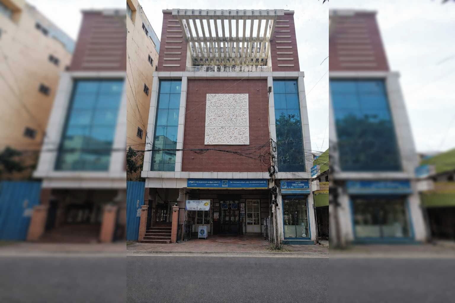 A modern building with a central atrium, large windows, and a blue sign indicating a bank.
