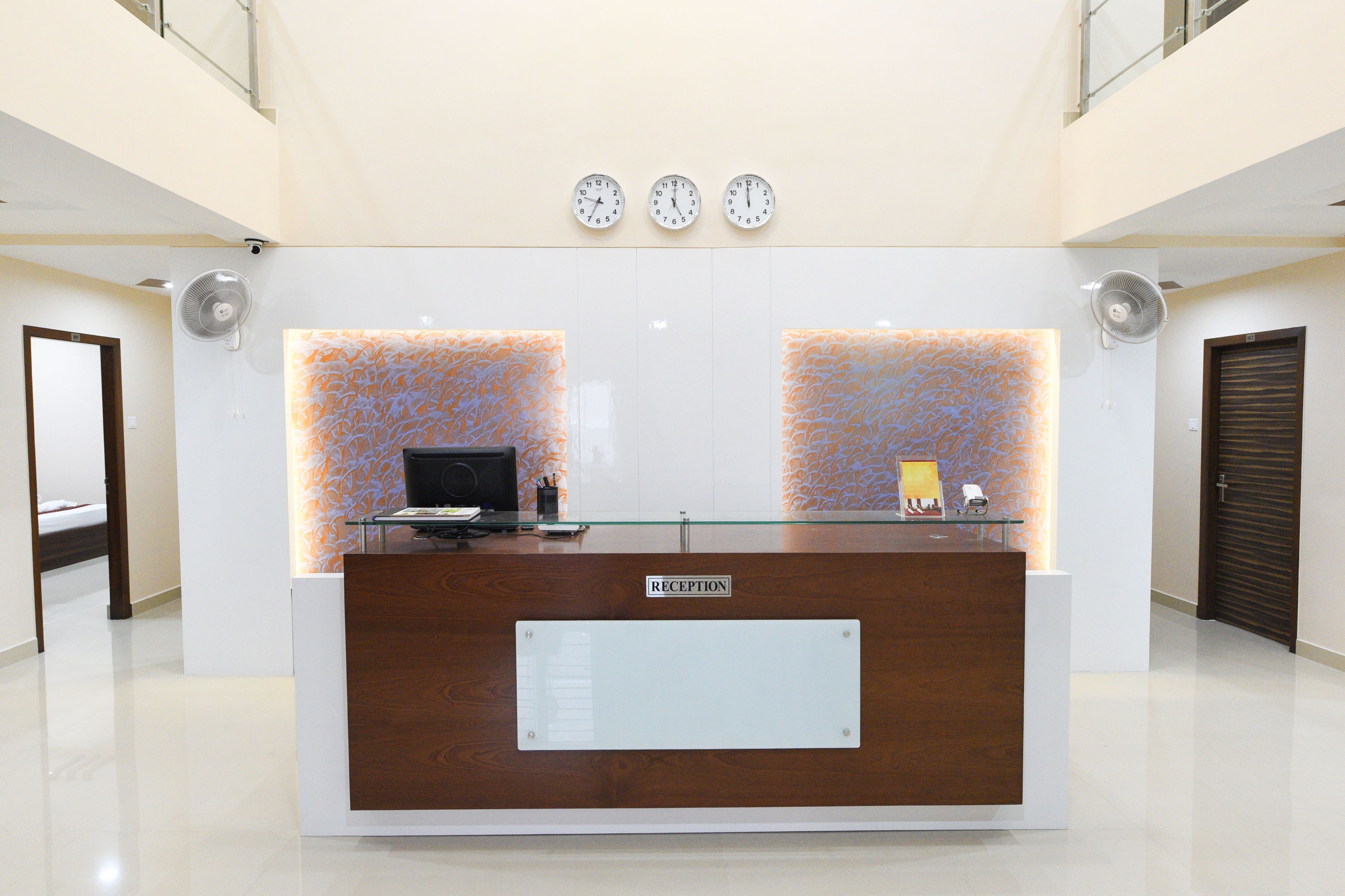 A reception desk with a wooden finish, a glass top, and a sign labeled 'RECEPTION'.