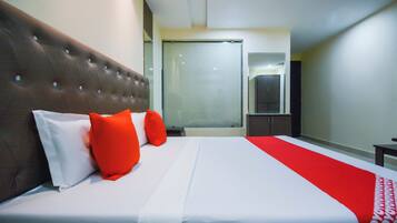 A hotel room with a large bed, a headboard with buttons, a wardrobe, and a mirror.