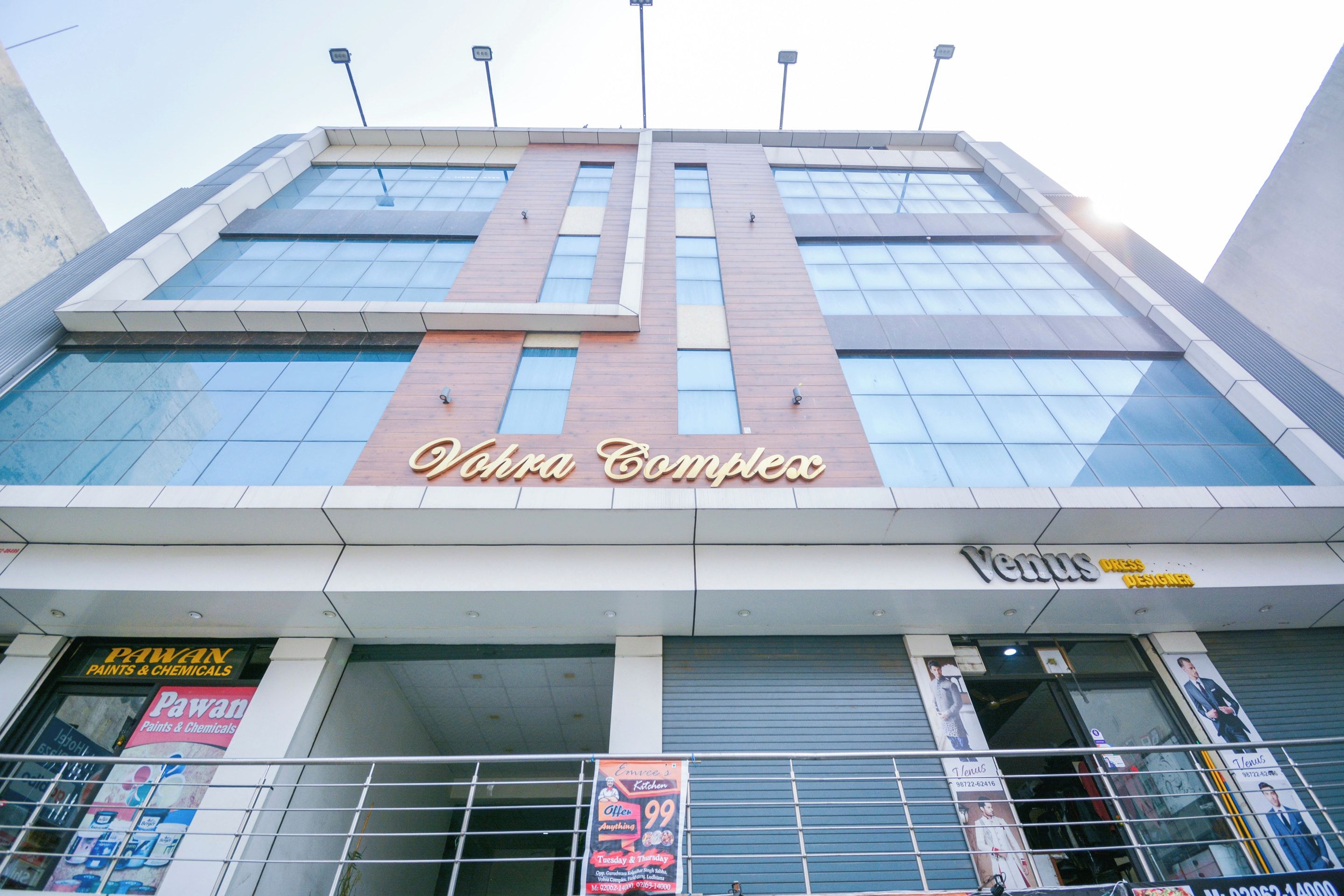 Un edificio con un letrero que indica 'Vohra Complex' y 'Venus Designer' en la planta baja.