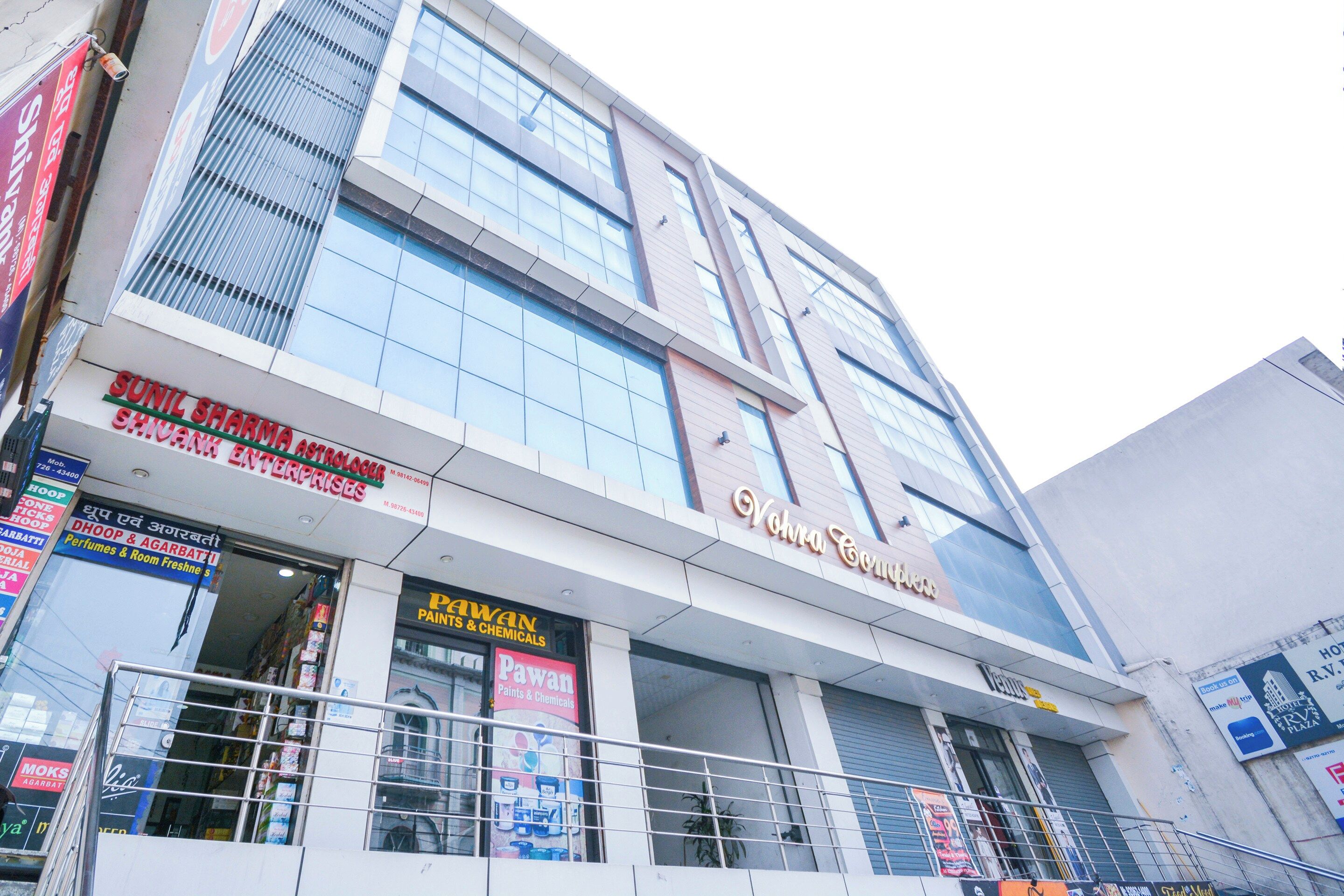 A multi-story commercial building with various storefronts, including a pharmacy, a paint store, and a hotel.