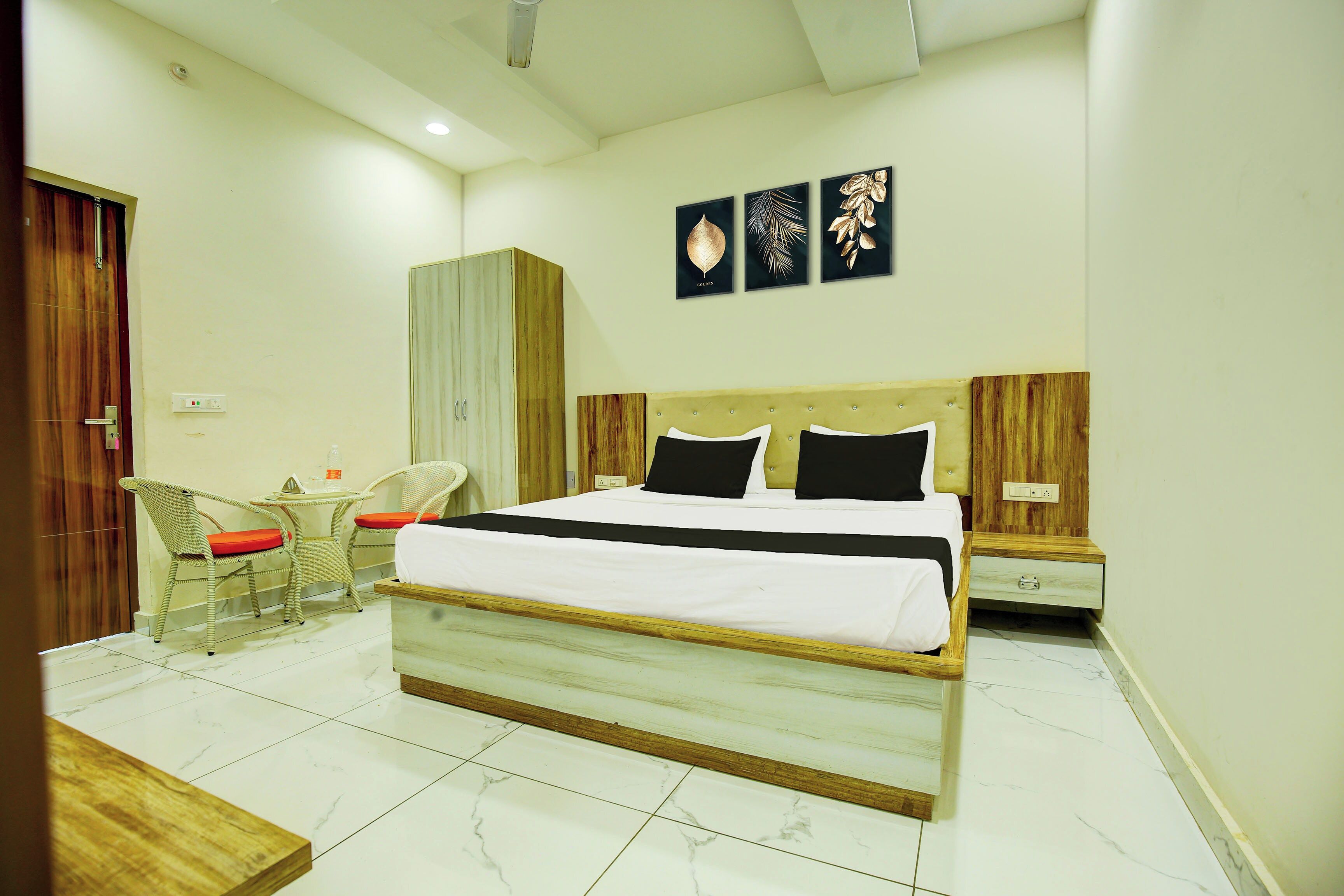 Un dormitorio con cama, mesitas de noche, armario, una silla y una pequeña mesa.