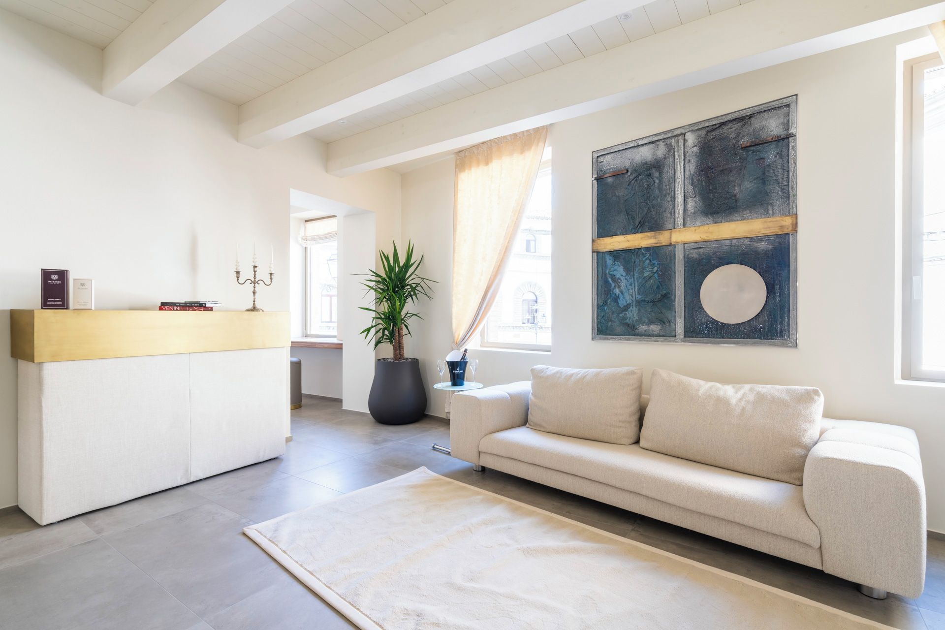 Ein modernes Wohnzimmer mit einer Couch, einem Couchtisch, einem großen abstrakten Gemälde und einer Topfpflanze.