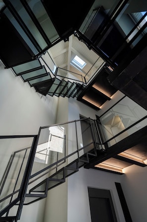 A multi-level interior with a glass staircase and skylights.