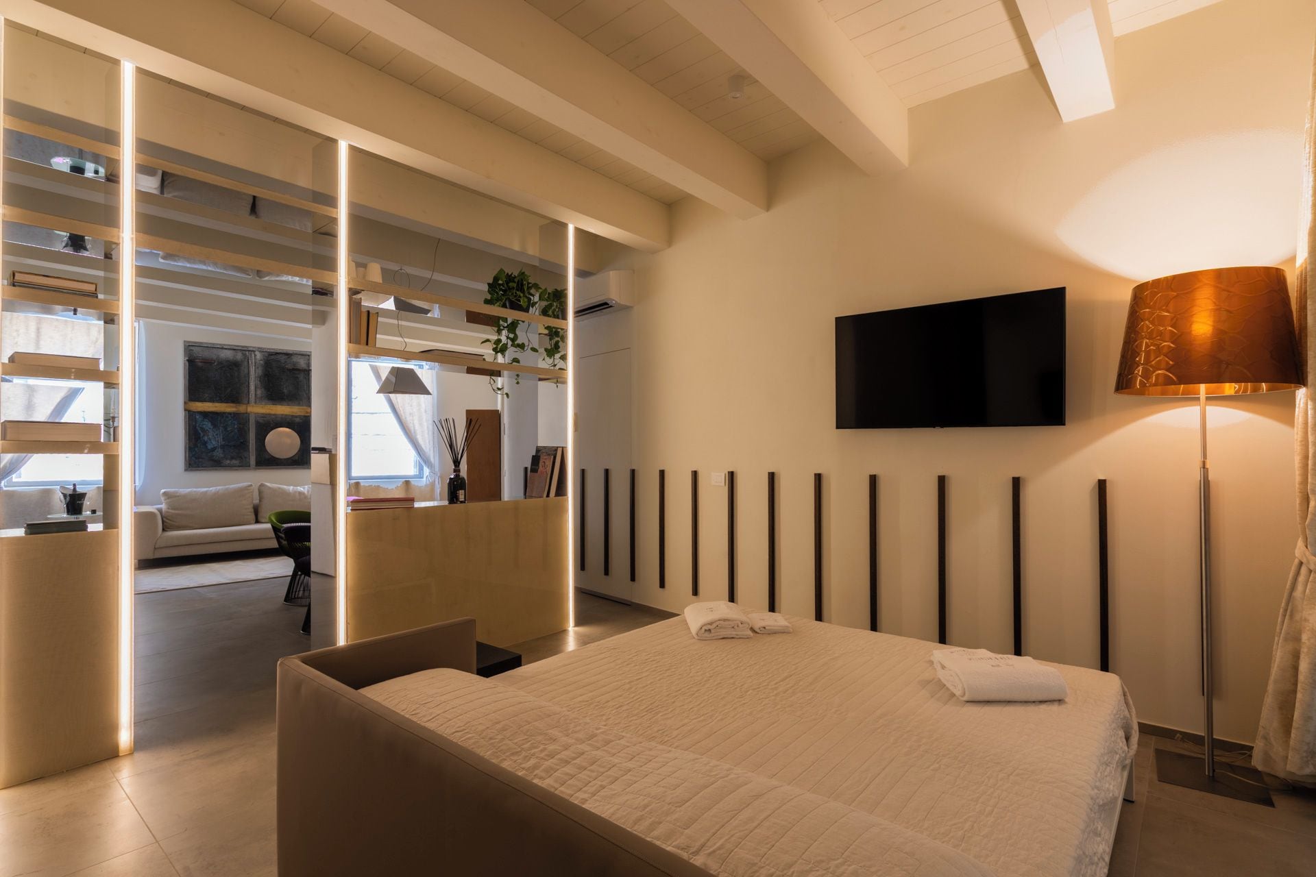 Ein modernes Schlafzimmer mit einem Bett, einem Fernseher und einer Nachttischlampe.