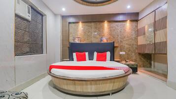 A modern bedroom with a circular bed, a wooden headboard, and a marble wall.