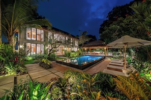 A two-story building with a swimming pool surrounded by tropical plants and a gazebo. - Elegant 5BR Villa in Tropical Ubud with Pool+Patio (Gianyar Regency)
