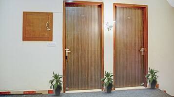 Two wooden doors with numbers 202 and 201, a small square mirror, and two potted plants on a carpeted floor.