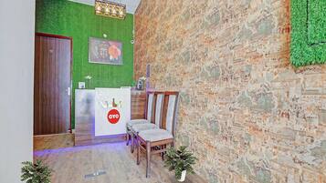 A reception area with a wooden reception desk, a green wall, and a brick wall.