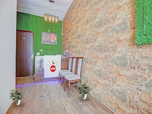 Una zona de recepción con mostrador de madera, pared verde y pared de ladrillo.