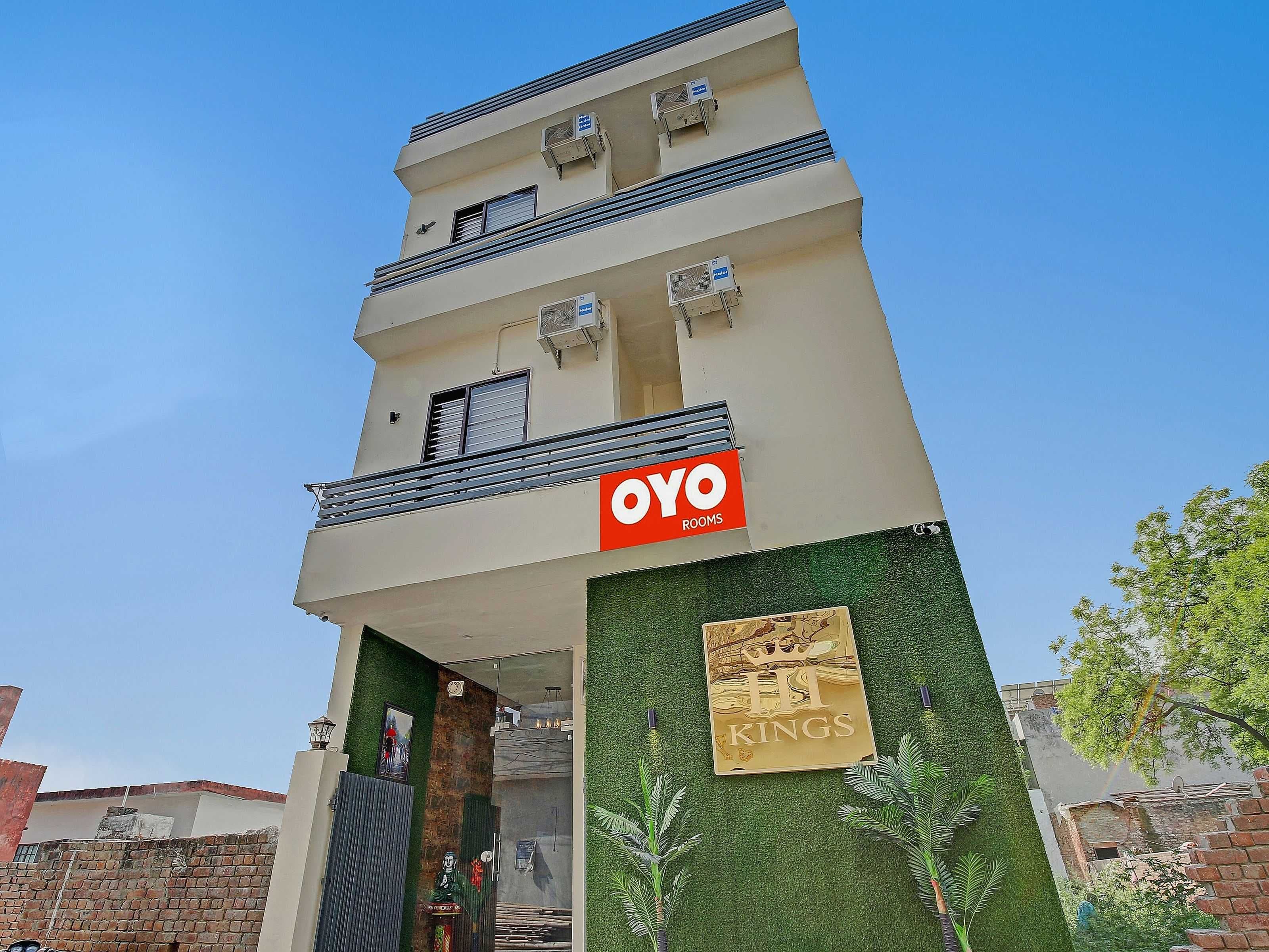 A hotel with a prominent 'OYO ROOMS' sign, a balcony, and a green wall with a 'HI KINGS' sign.