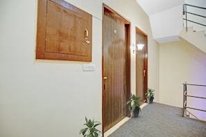 Un pasillo con puertas de madera, un interruptor de luz y dos plantas en macetas.