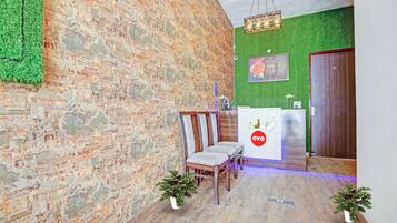 Un área de recepción con pared verde, mostrador de madera, una silla y una estatua de Buda.