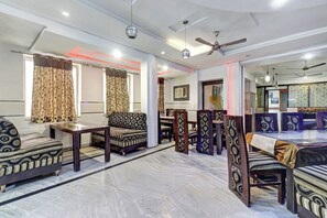 Amplia sala de estar con sofá, mesa de comedor y sillas, que cuenta con un ventilador de techo moderno e iluminación decorativa.