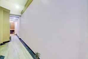 Un pasillo con piso de mármol, una planta en maceta y una puerta que da a otra habitación.