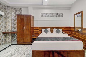 Habitación de hotel con cama, armario y espejo.