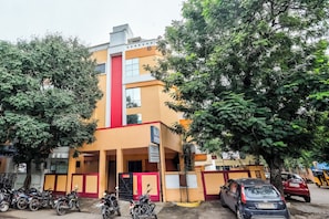 A multi-story building with a red and yellow facade, a visible staircase, and a gated entrance.