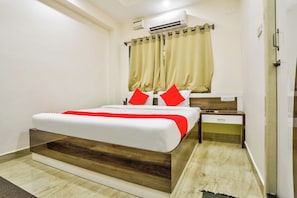 A hotel room with a bed, bedside tables, an air conditioning unit, and a door. - Hotel O Nimalan Residency (Chennai)