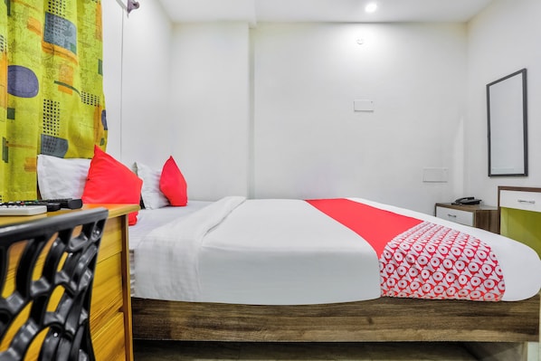 A hotel room with a bed, a bedside table, a chair, and a curtain.