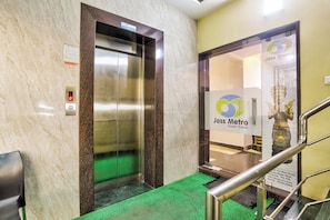 An elevator with a digital display, a safety warning sign, and a green carpeted entrance.