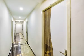 A corridor with a checkered floor, a door with a wooden panel, and a number '308' on the wall.