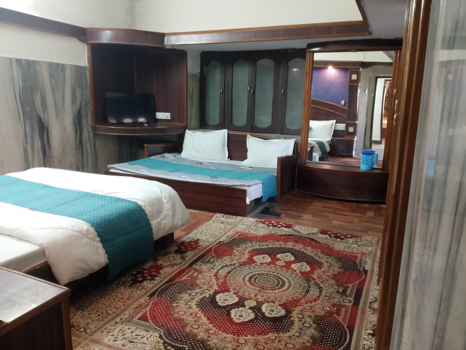 Une chambre à coucher avec un lit, un bureau, un miroir et un tapis à motifs.