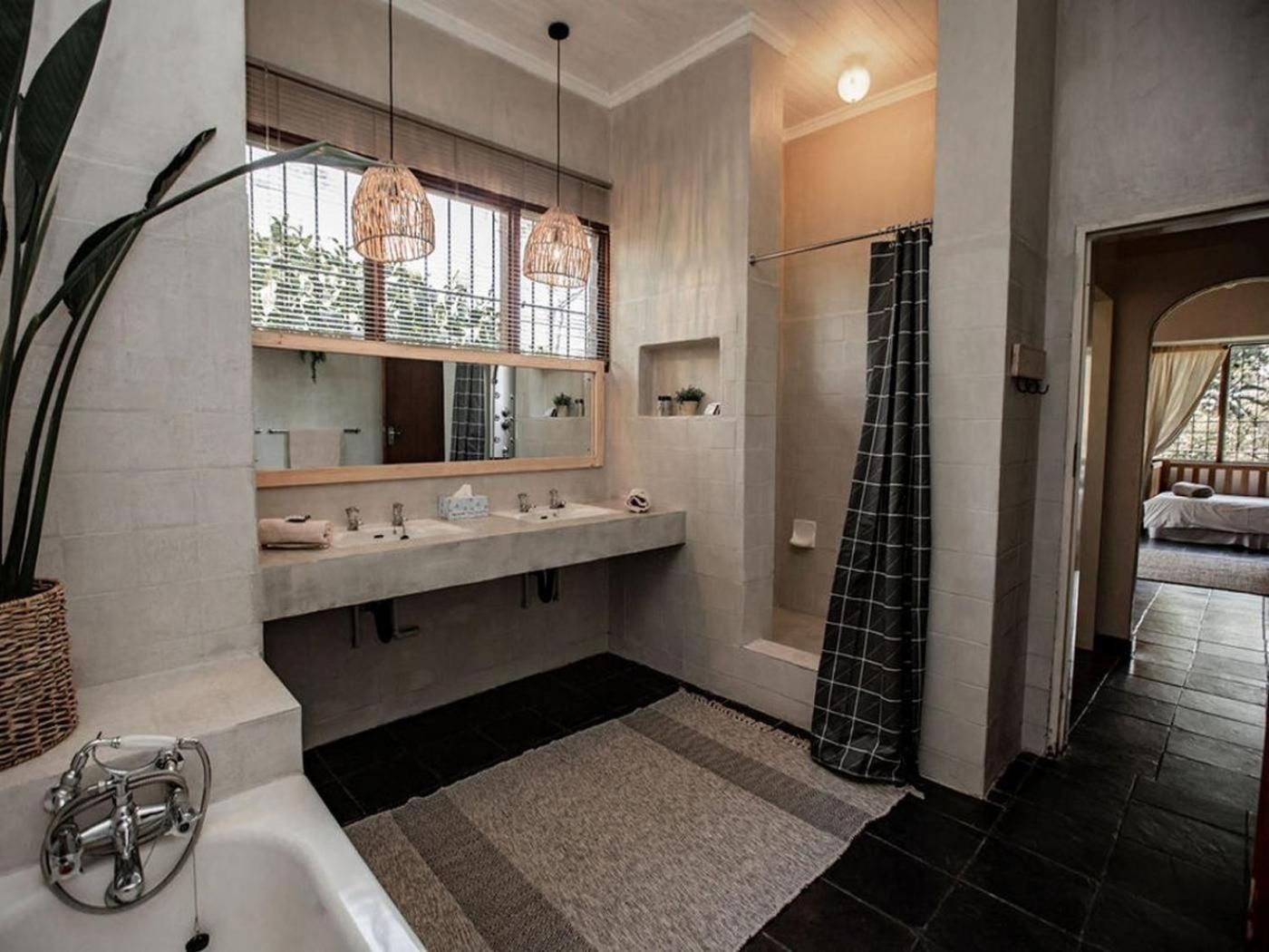 A modern bathroom with a large mirror, two sinks, a shower with a black curtain, and a bathtub.