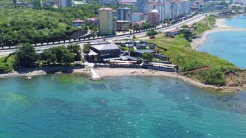 A coastal hotel with multiple buildings, a beach, and a road running parallel to the water.