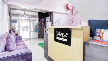 A reception area with a reception desk, a purple sofa, and a staircase.
