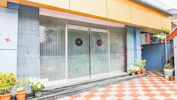 A building with a checkered floor, a glass door with a red symbol, and potted plants.
