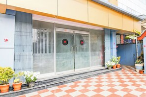 A building with a checkered floor, a glass door with a red symbol, and potted plants. - Super Collection O SF Road Siliguri (Siliguri)