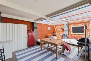 Ein kompakter Wohnraum mit Essbereich, einer kleinen Küche und einer Sitzecke mit Blick durch ein Dachfenster.