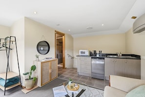 A modern apartment with a kitchenette, a living area with a sofa, and a dining table. - Cosy Bush Studio Near Airport (Acton Park)