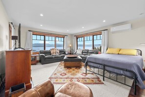 A spacious room with a large bed, a sofa, a desk, and a view of a lake. - Lakeview Retreat 4BR Home (Somers)