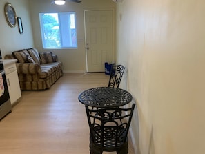 A dining area with a round table and chairs, a sofa, and a door in the background.