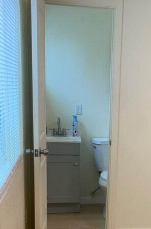 A narrow bathroom with a toilet, a sink, and a cabinet.