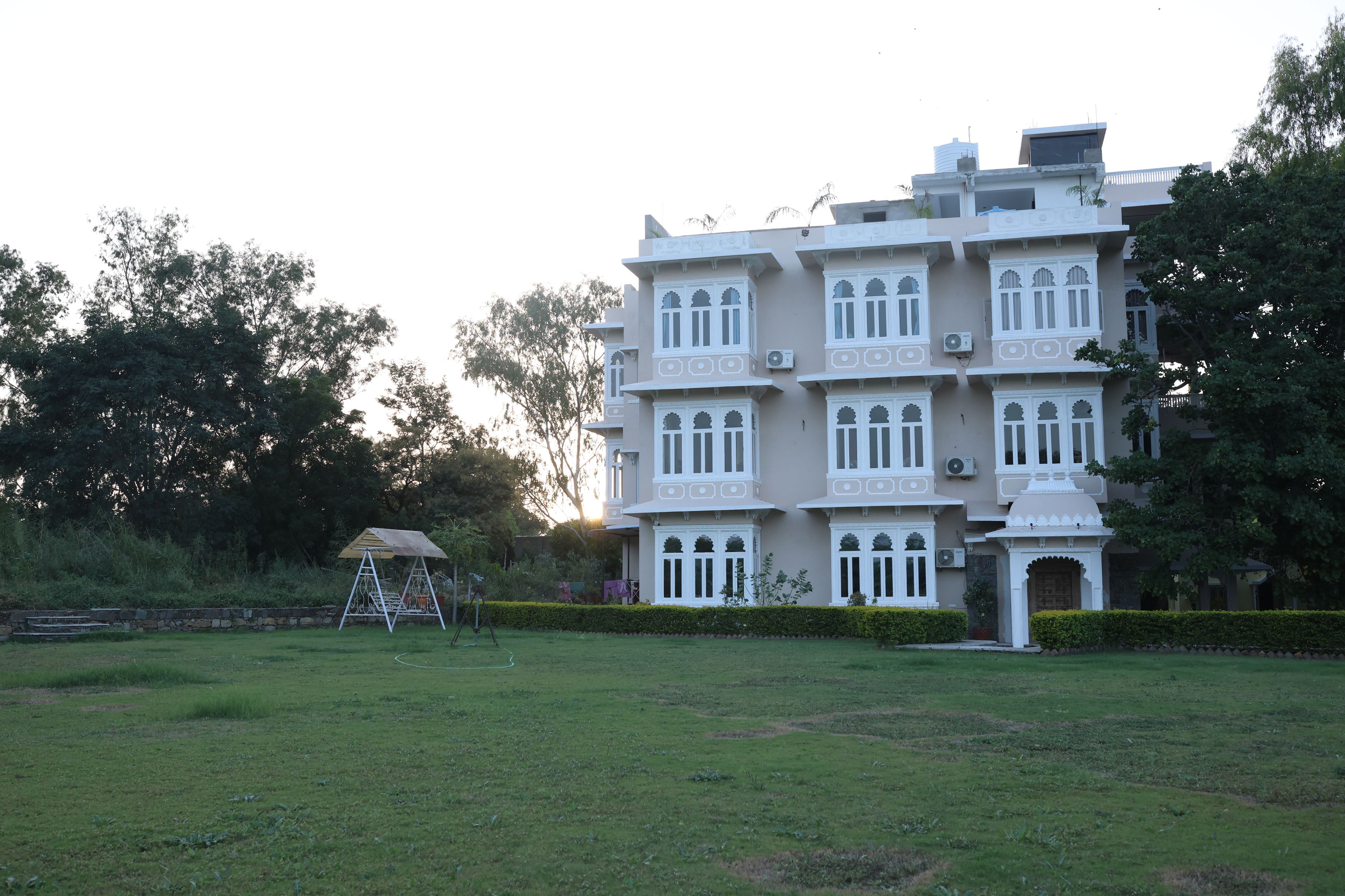 A multi-story building with a traditional architectural style, featuring multiple balconies and a well-maintained lawn in the foreground.