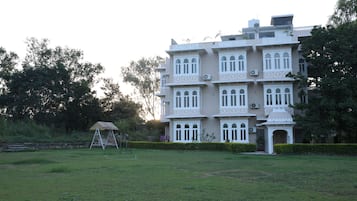 A multi-story building with a traditional architectural style, featuring multiple balconies and a well-maintained lawn in the foreground.