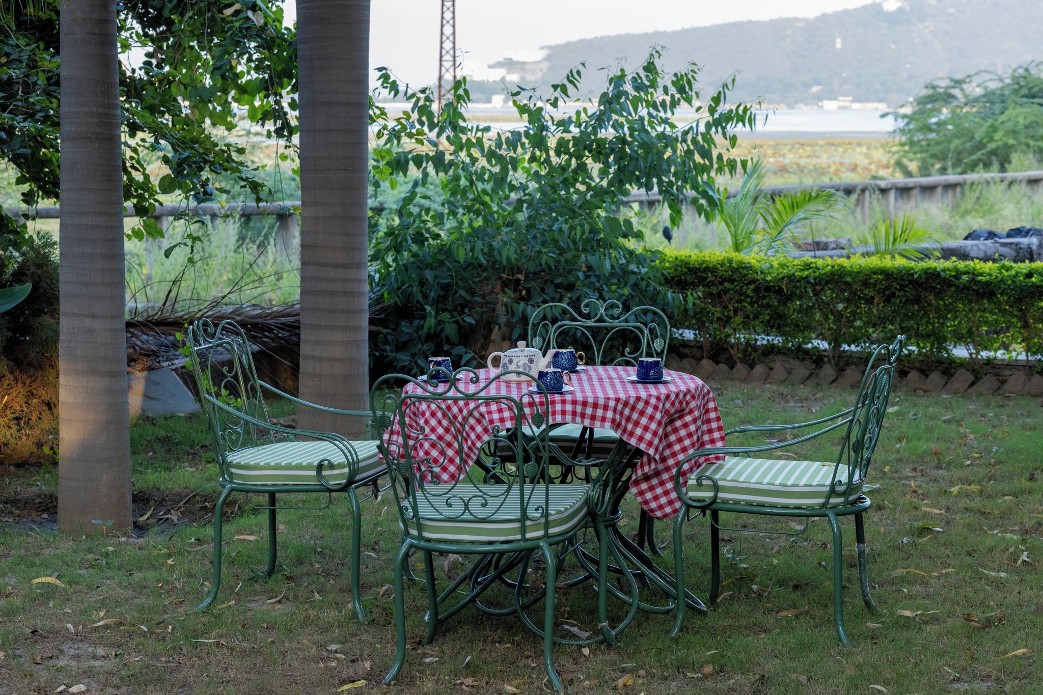 An outdoor dining area with a checkered tablecloth, metal chairs, and a view of a body of water in the background.
