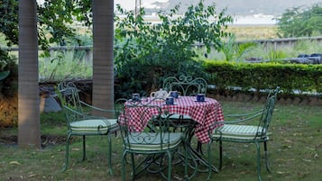 An outdoor dining area with a checkered tablecloth, metal chairs, and a view of a body of water in the background.