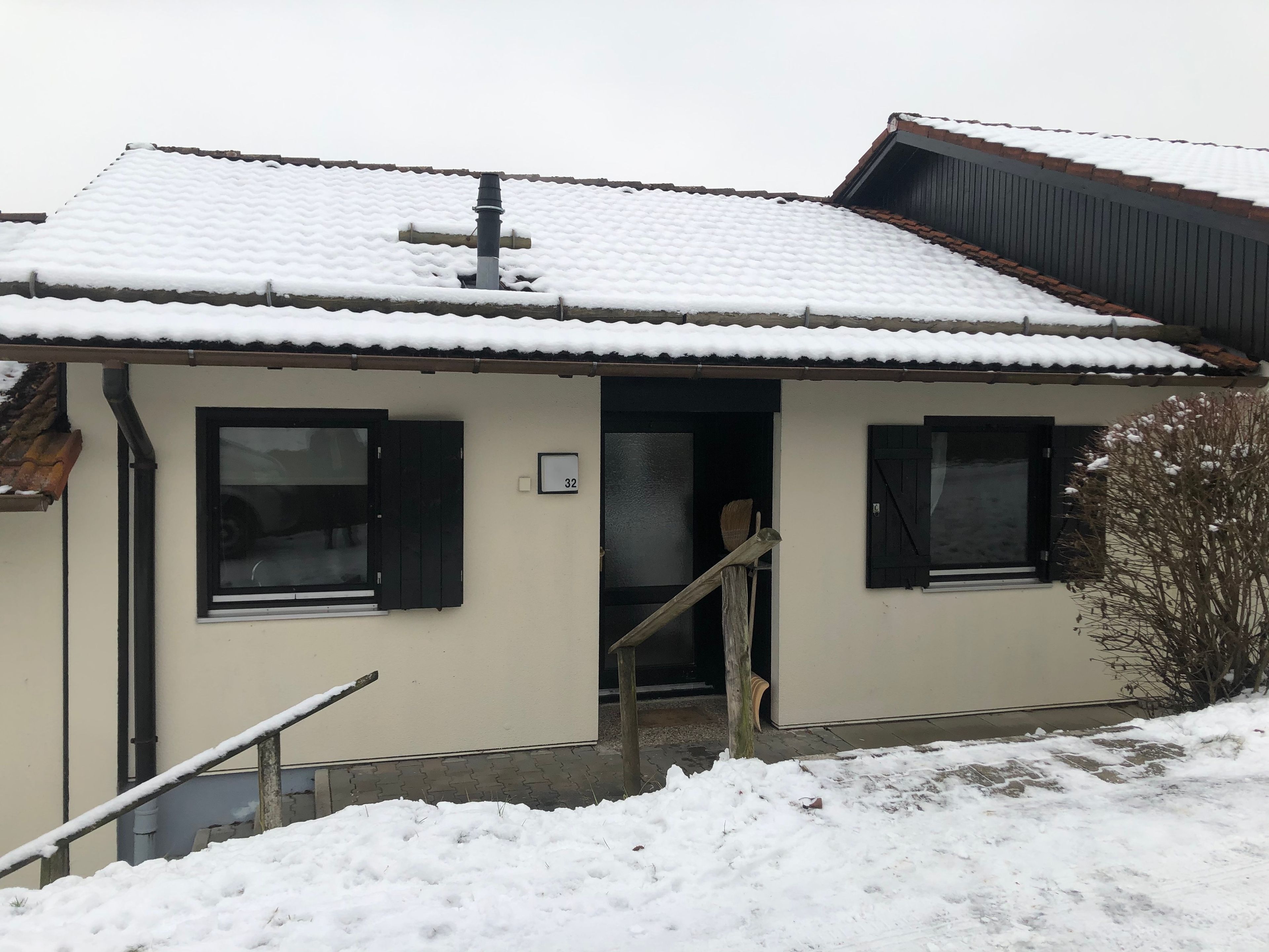 Ein zweistöckiges Gebäude mit schneebedecktem Dach und der Hausnummer 32 an der Wand.
