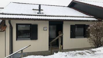 Ein zweistöckiges Gebäude mit schneebedecktem Dach und der Hausnummer 32 an der Wand.