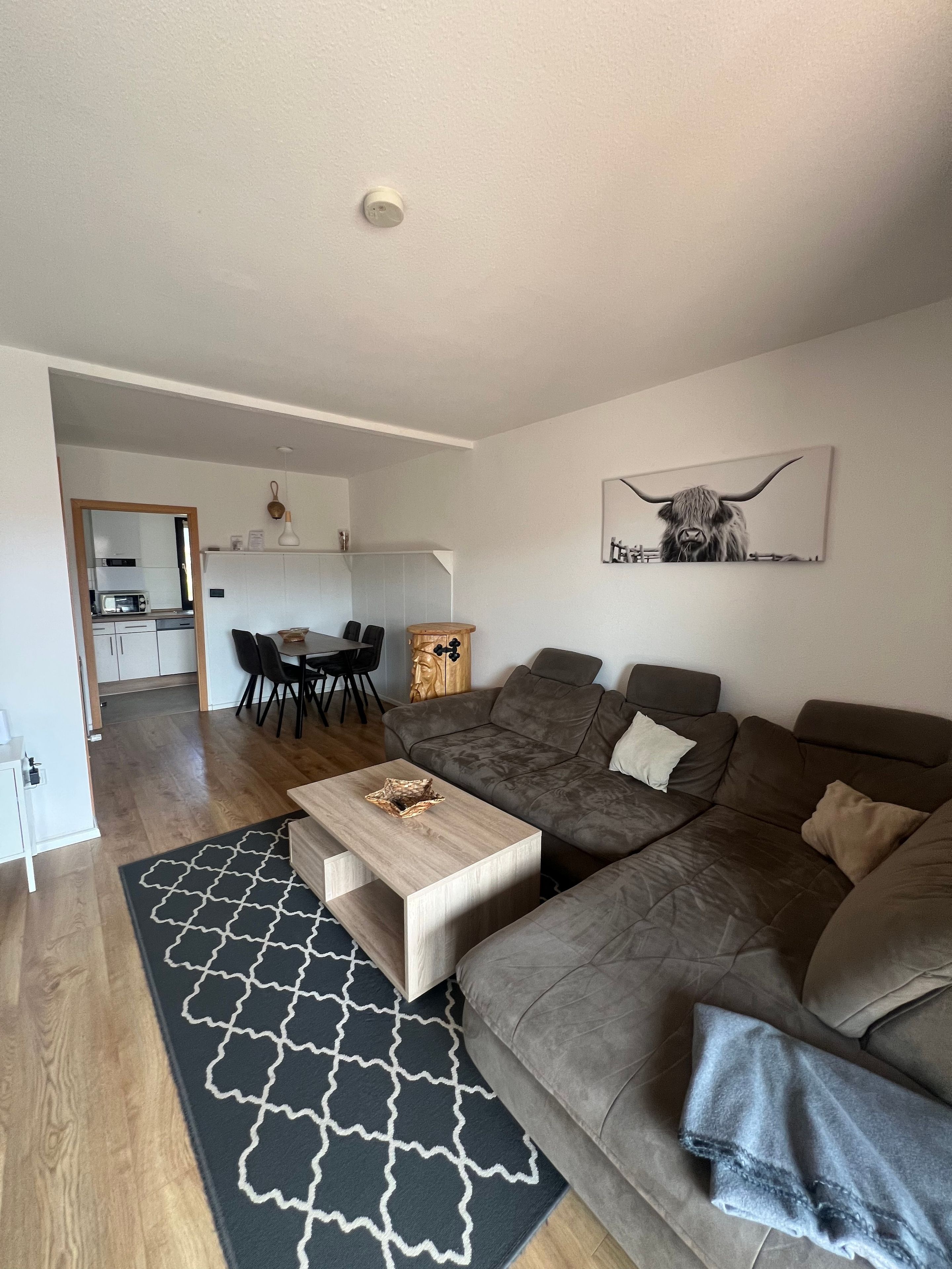 Ein modernes Wohnzimmer mit einer Couch, einem Couchtisch und einem Essbereich mit Stühlen.