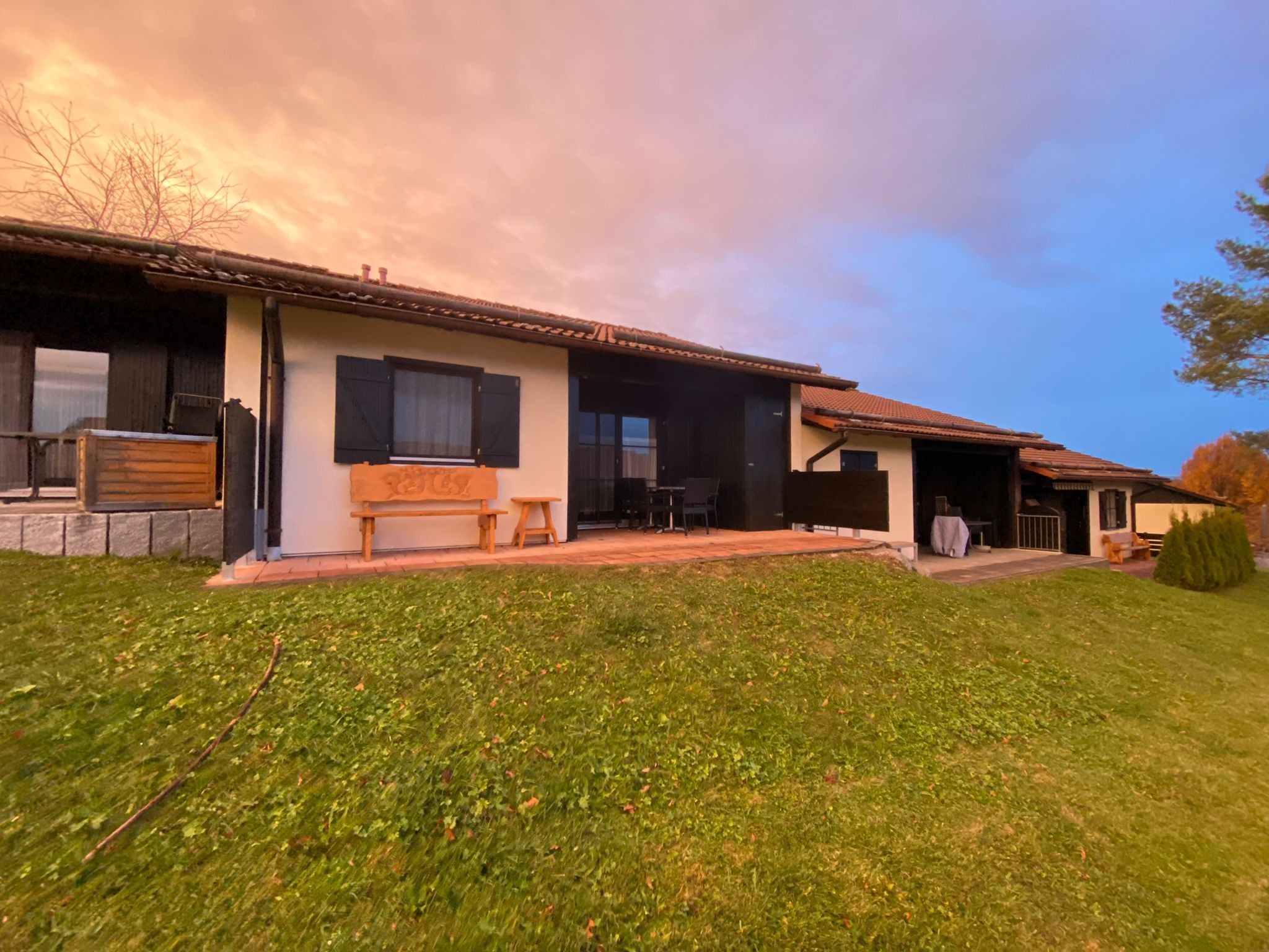 A two-story house with a patio, a bench, and a covered outdoor seating area.
