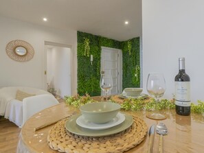 A dining area with a table set for two, a bottle of wine, and a green wall with plants. - CHL La Palma Beach Infront of the sea (Santa Cruz de la Palma)