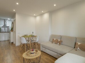 A modern living room with a sofa, a dining table with chairs, and a kitchen area in the background. - CHL La Palma Beach Infront of the sea (Santa Cruz de la Palma)