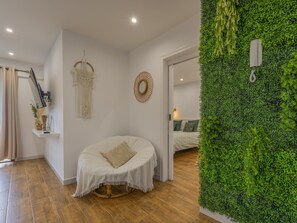 Ein Zimmer mit einem runden Bett, einem Wandbehang aus Makramee und einer grünen Wand mit einem hängenden Telefon.