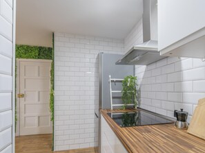 A kitchen with white tiled walls, a wooden countertop, a built-in stove, and a hanging plant. - CHL La Palma Beach Infront of the sea (Santa Cruz de la Palma)